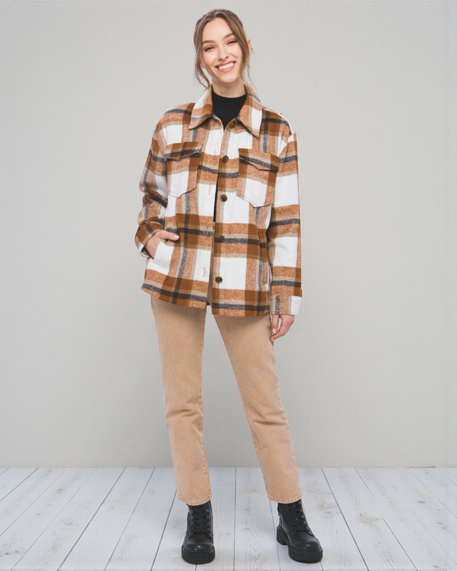 Woman wearing a plaid shirt and beige pants against a plain background