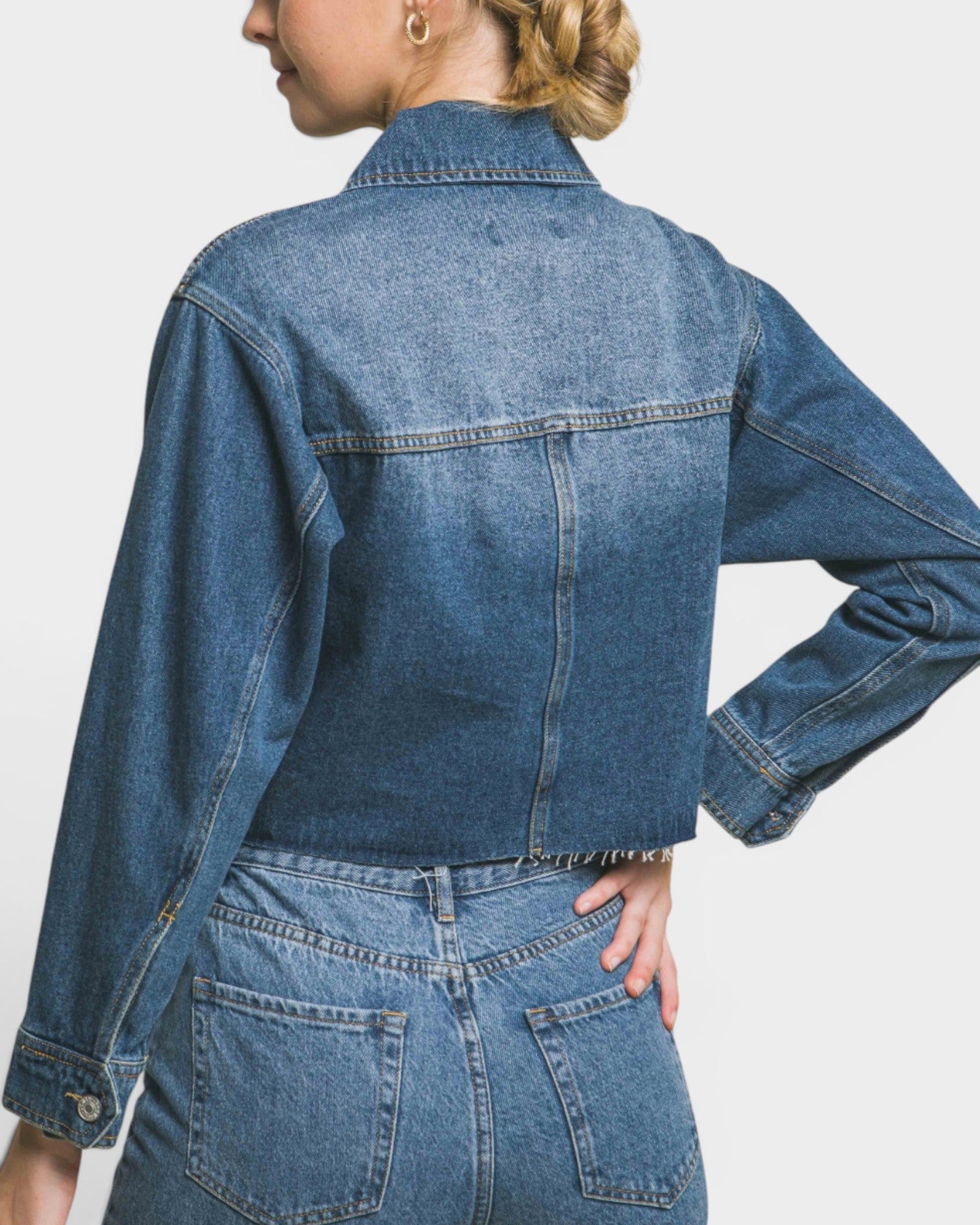 Person wearing a blue denim jacket on a plain background