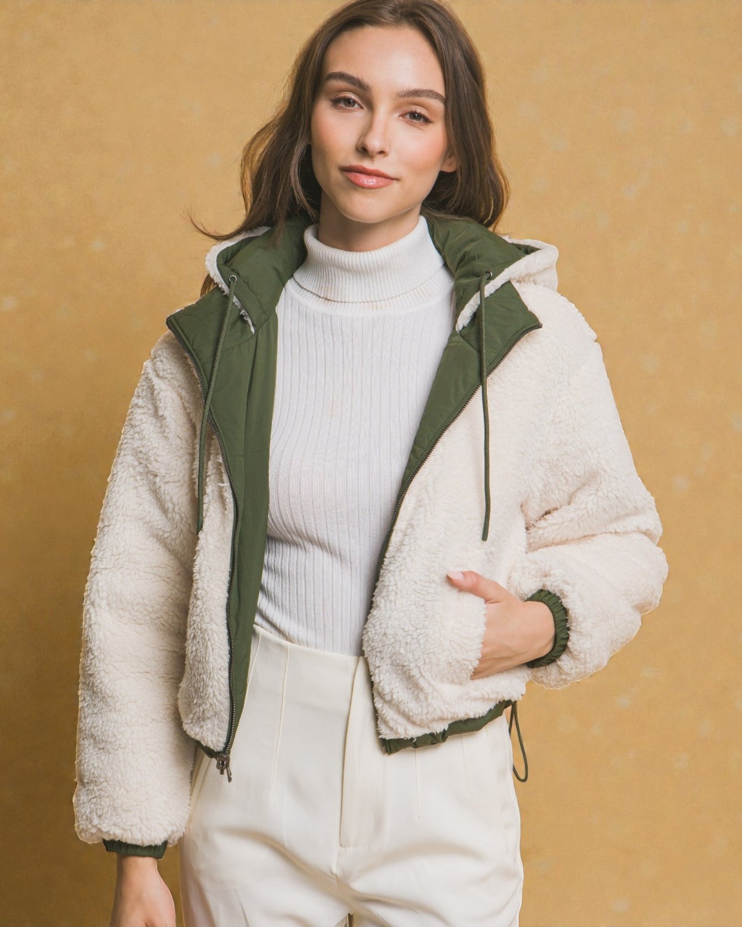 Woman wearing a white puffer jacket with green trim against a beige background