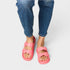 Pink sandals worn with blue jeans on a light gray background