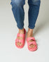 Person wearing bright pink sandals and blue jeans on a plain background