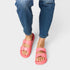 Pink sandals worn with blue jeans on a white background