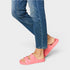 Person wearing blue jeans and pink sandals on a light gray background