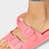 Pink slide sandal worn on a foot against a light gray background