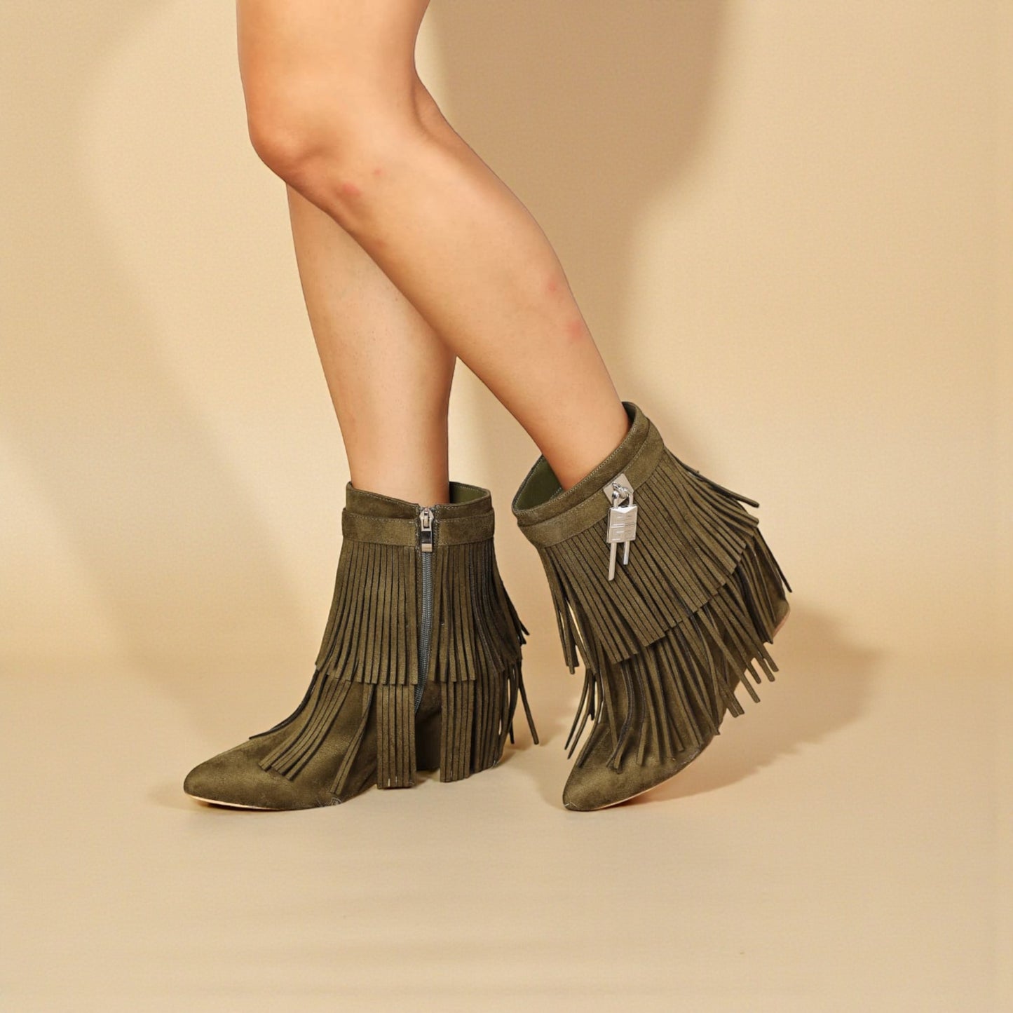 Green fringe boots worn by a person on a beige background