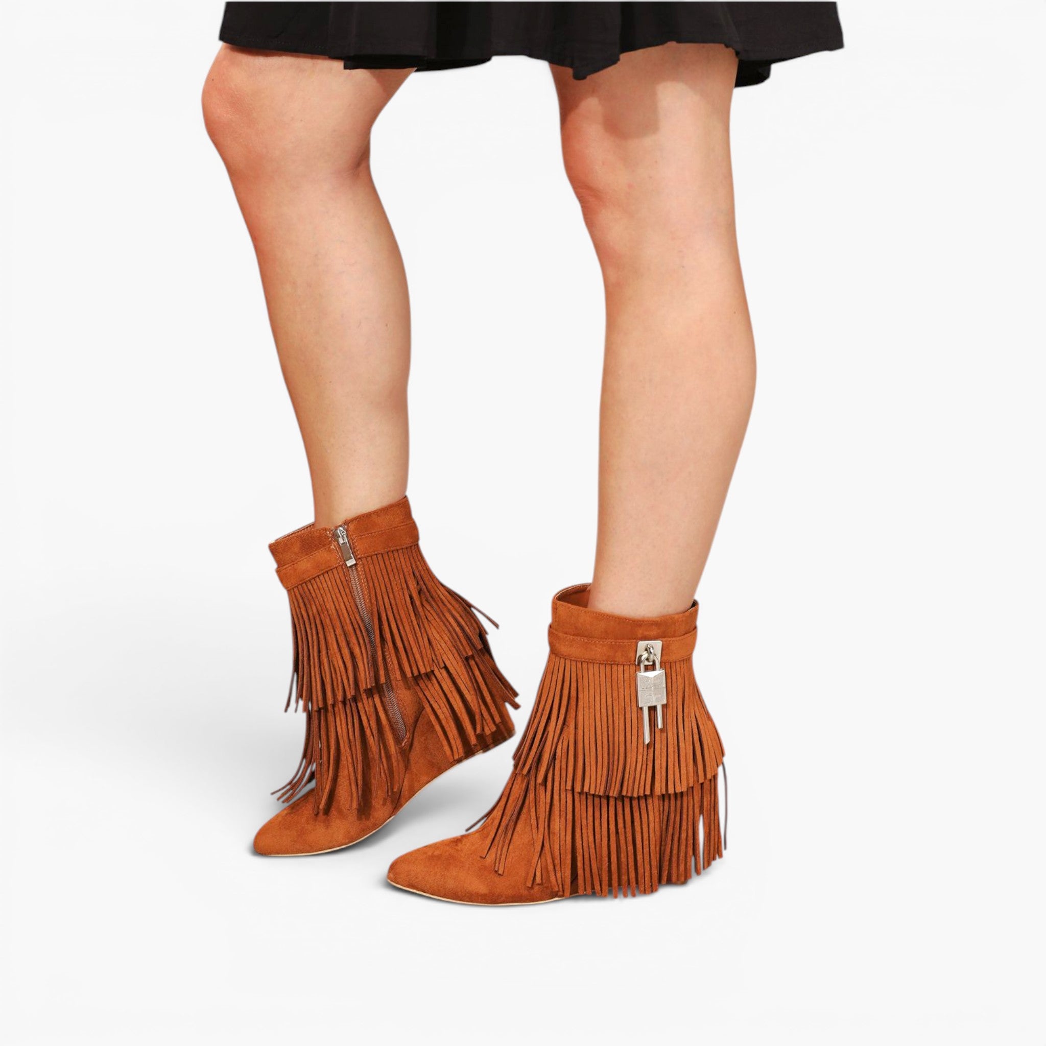 A pair of women's brown suede ankle boots with long fringe and a low block heel, shown on a model's feet against a light gray studio background.