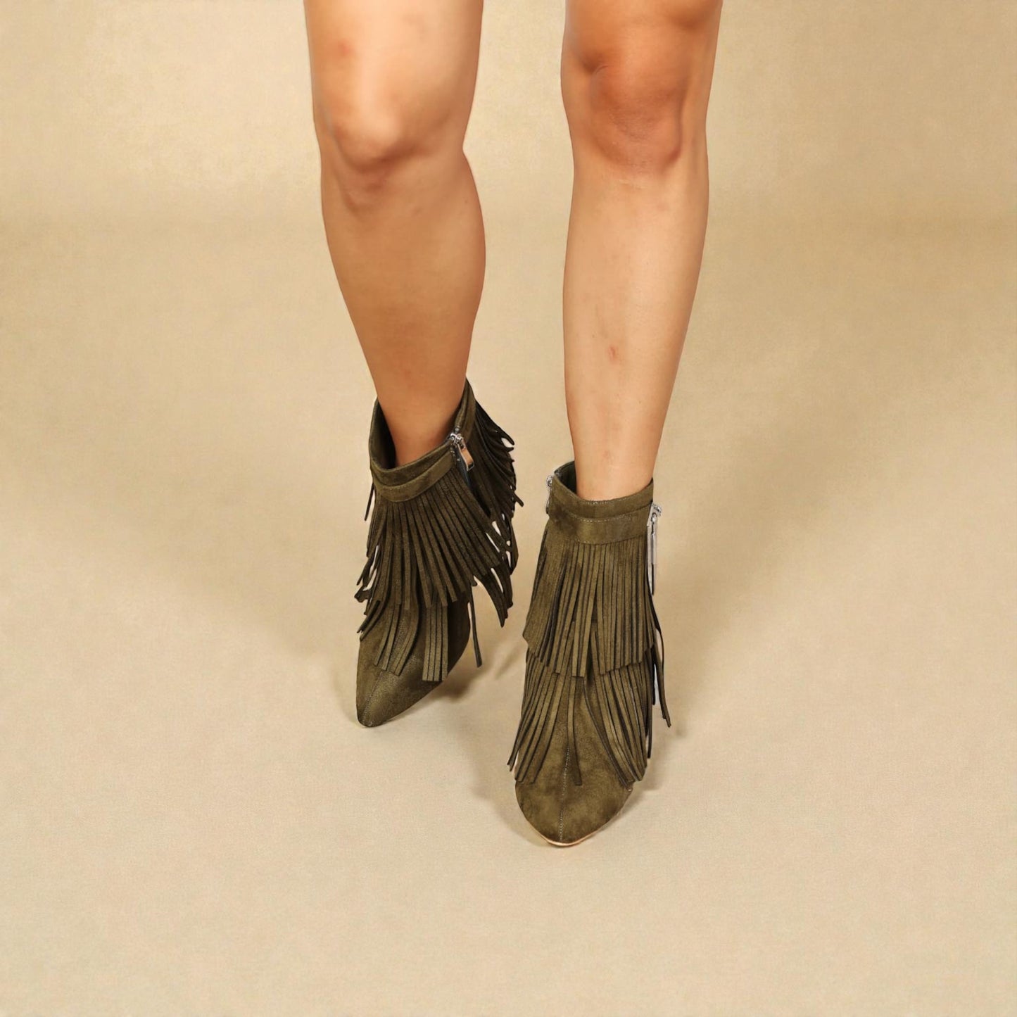 Green fringed boots worn by a person on a beige background