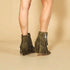 Green fringe boots worn by a person on a beige background