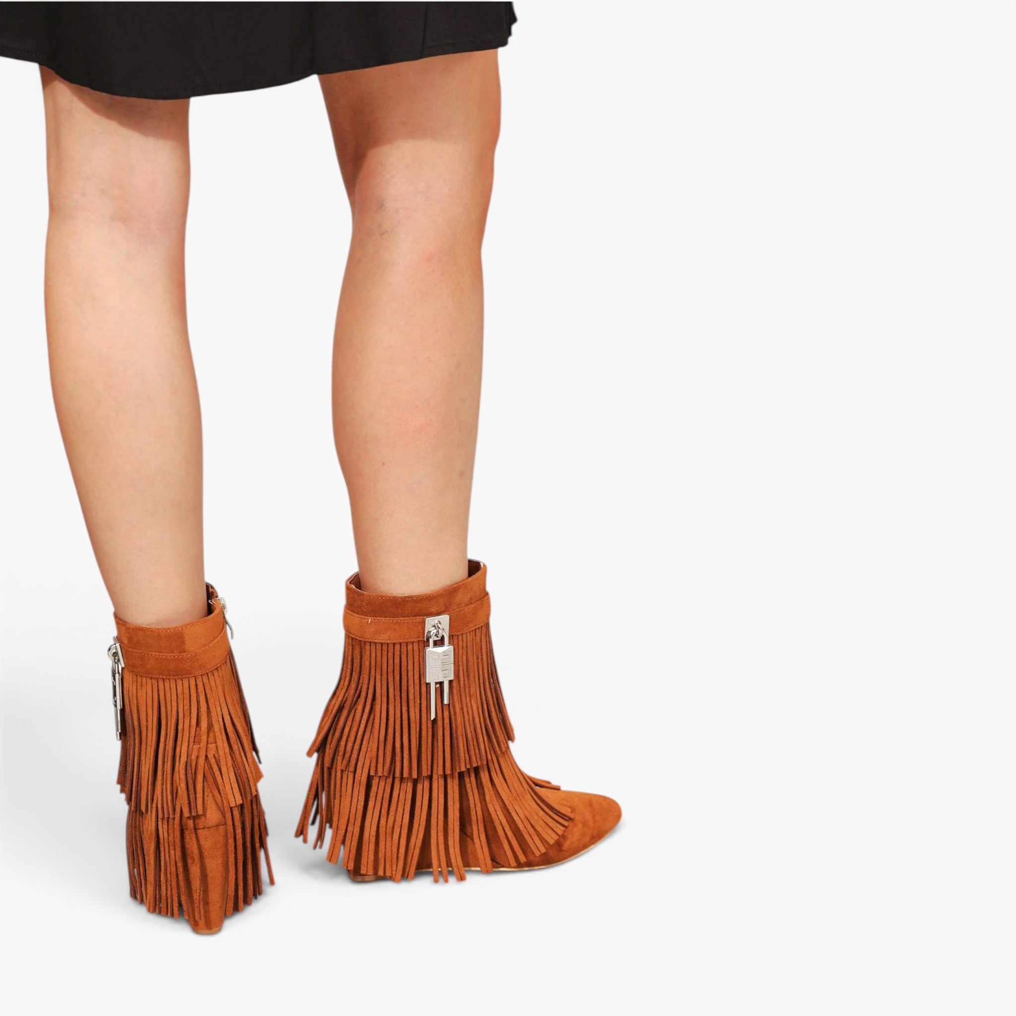 A pair of women's ankle boots in a warm brown suede-like material, featuring long fringe cascading down the sides and a small silver padlock detail on the front, shown on a model's feet against a light gray background.