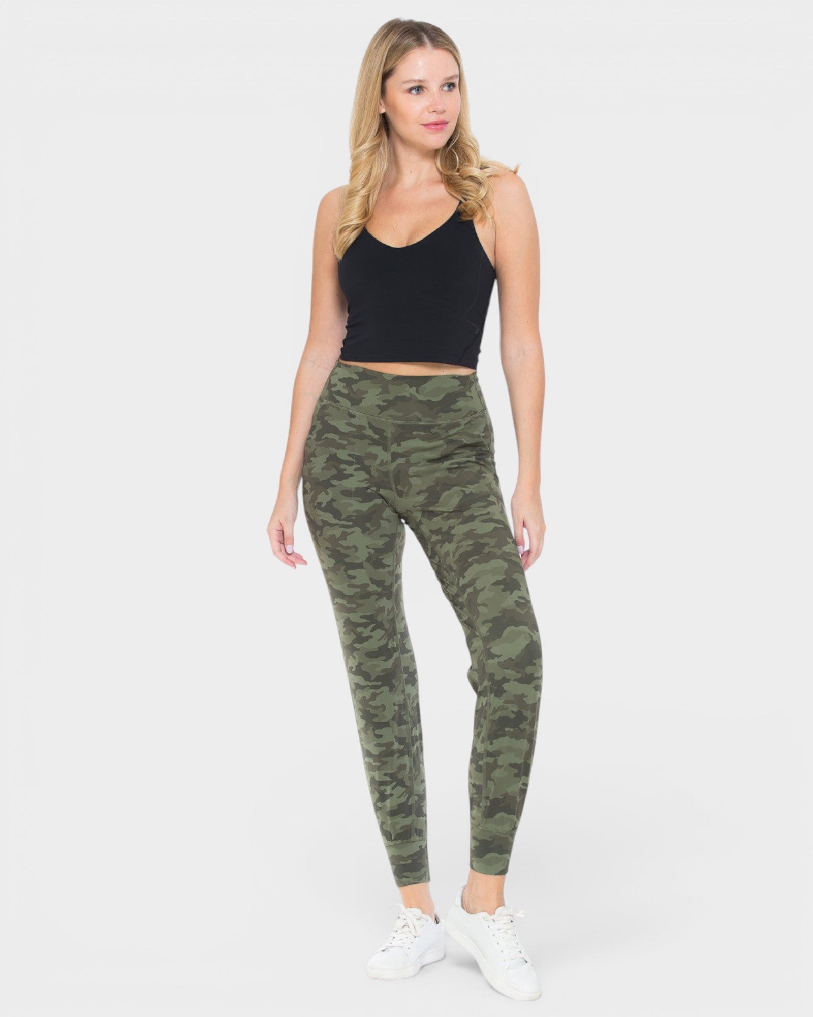 Woman wearing camouflage leggings and a black top on a white background