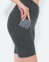 Person wearing dark gray athletic shorts with a pocket holding a phone on a white background