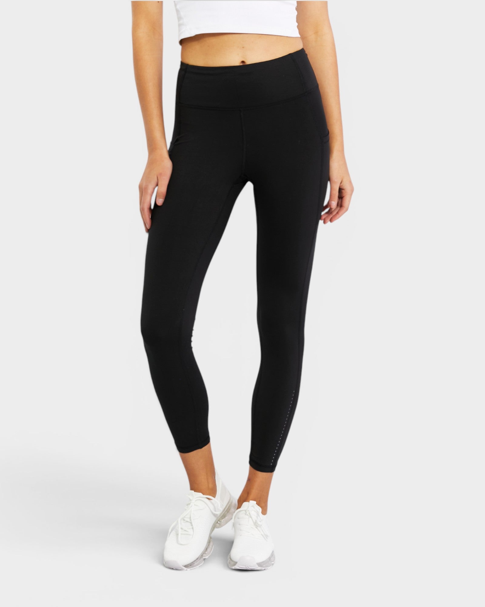 Person wearing black leggings and white sneakers on a white background