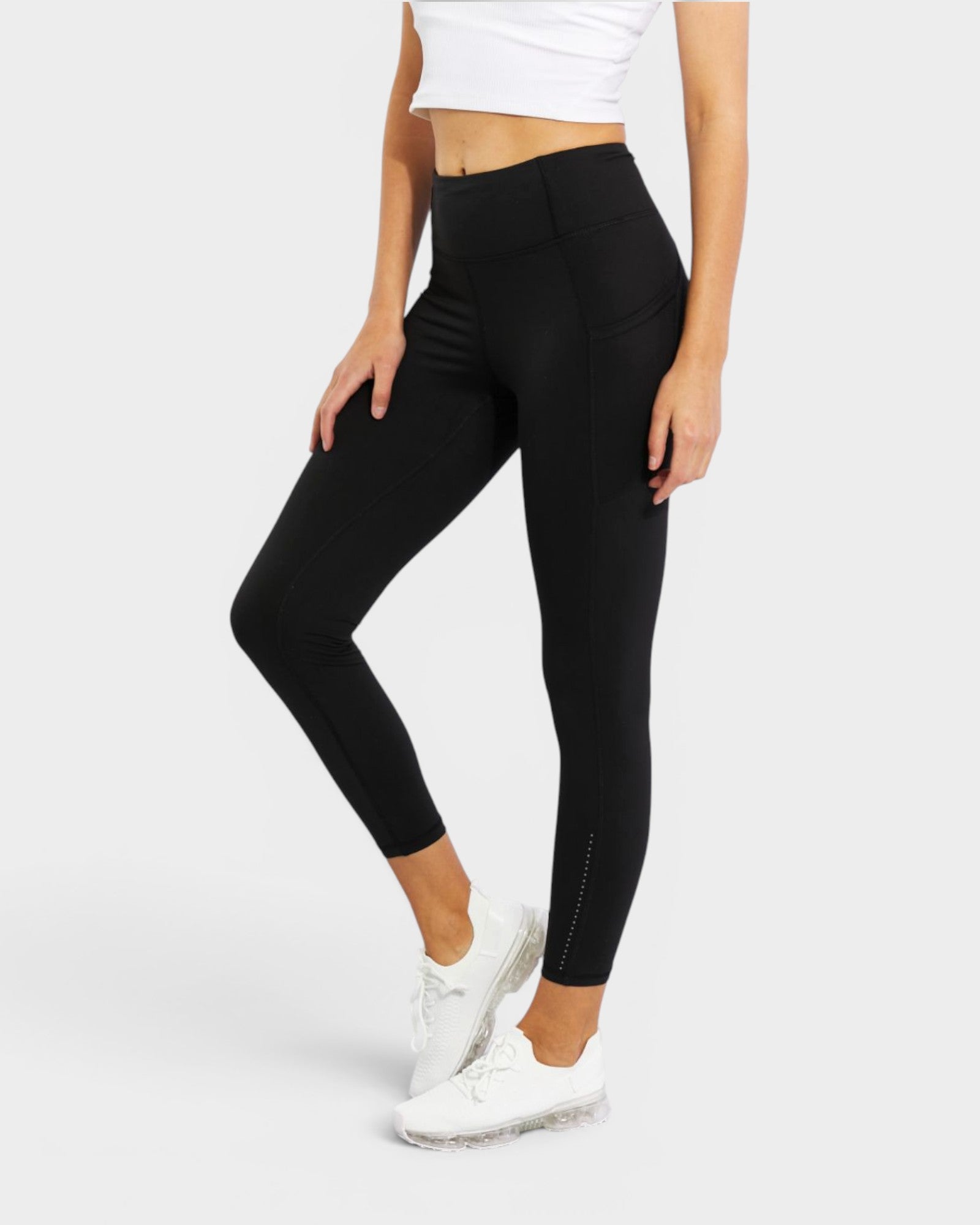 Person wearing black leggings and white sneakers on a white background