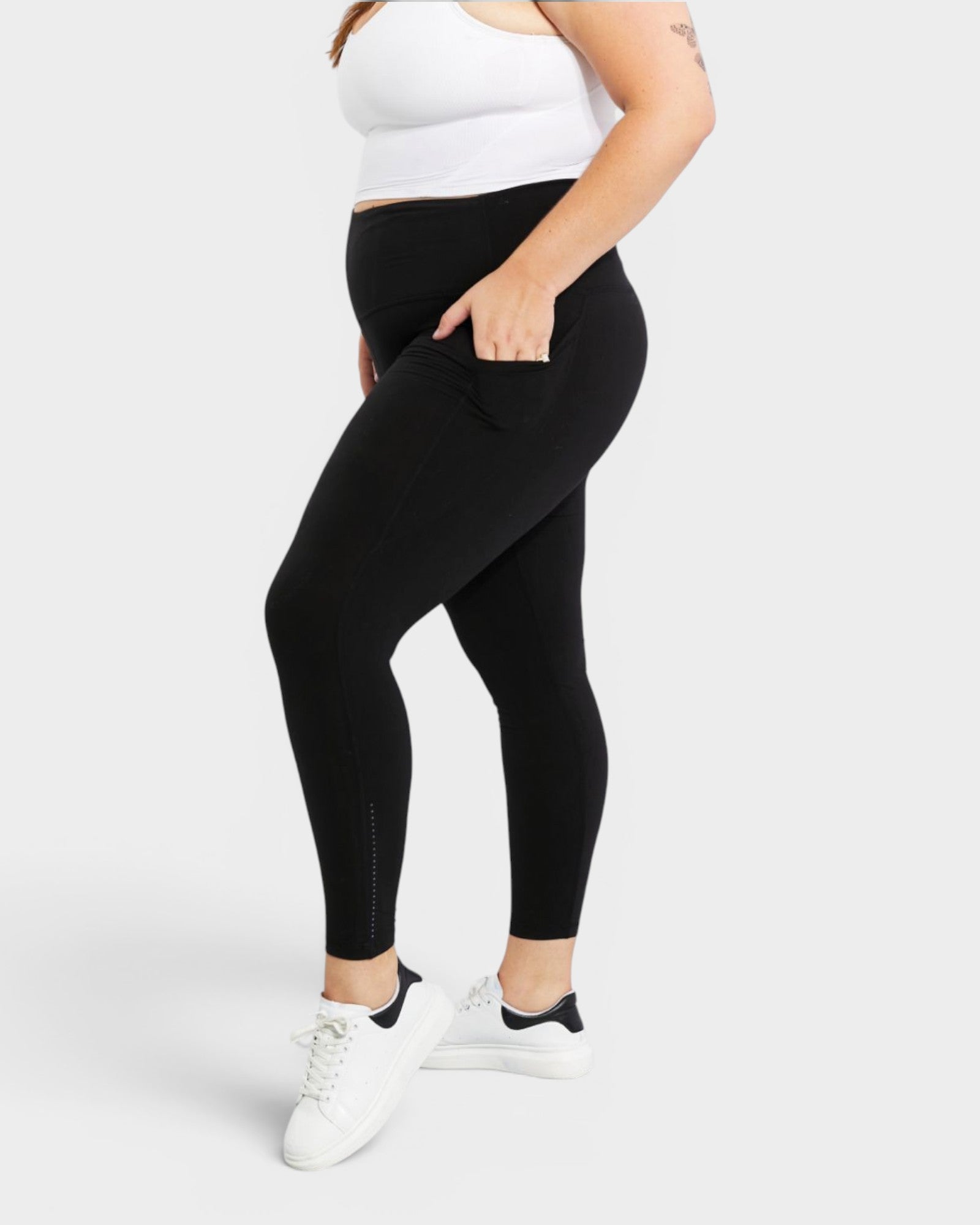 Person wearing black leggings and white sneakers on a white background