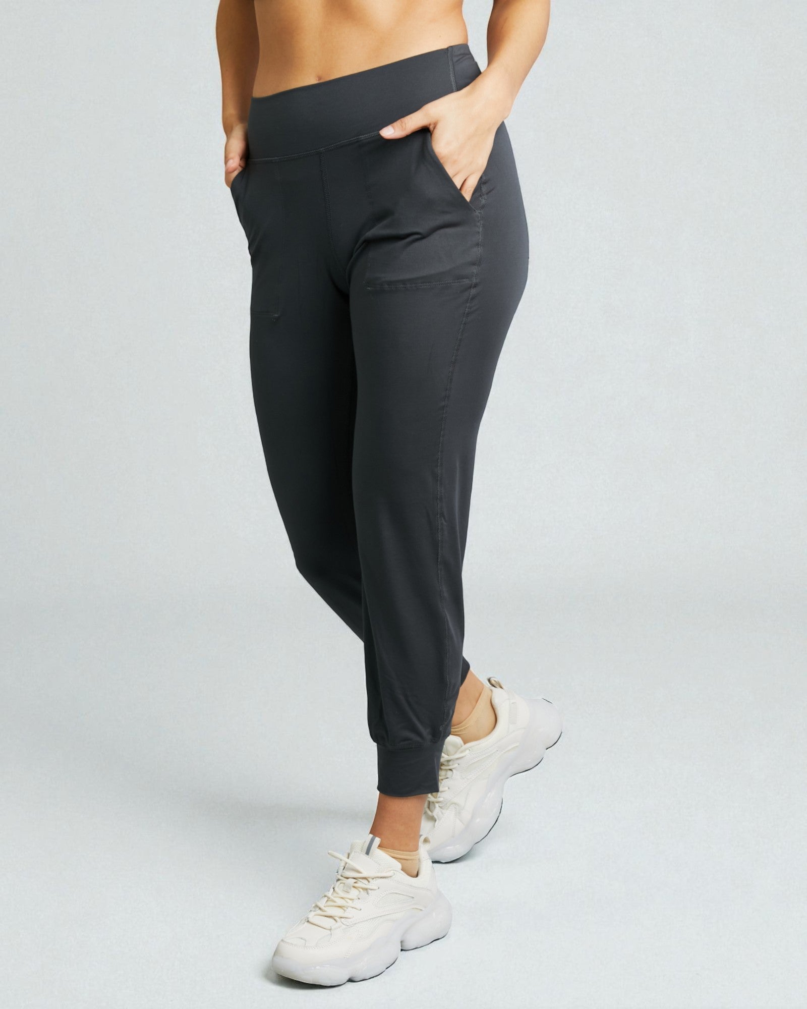 Person wearing black jogger pants on a light gray background
