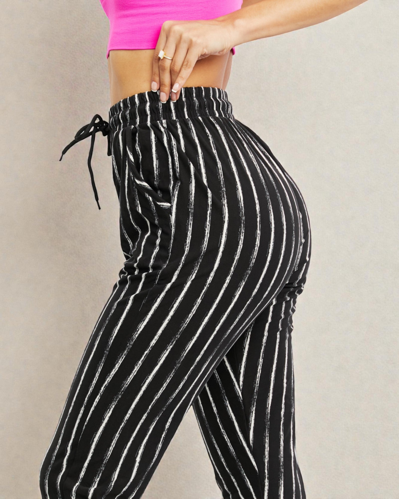 Black and white striped pants with a pink top on a neutral background