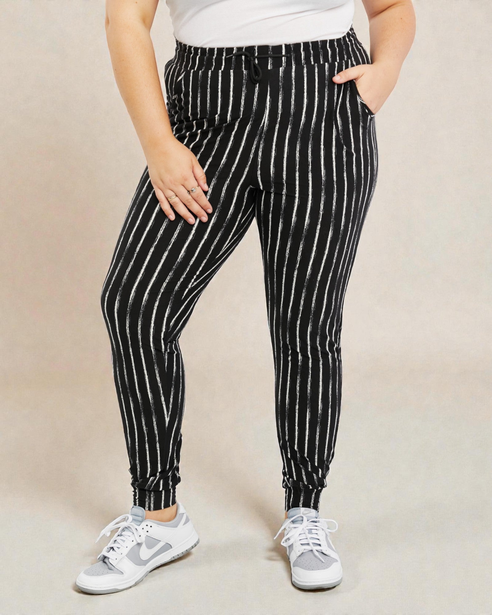 Person wearing black and white striped pants on a beige background