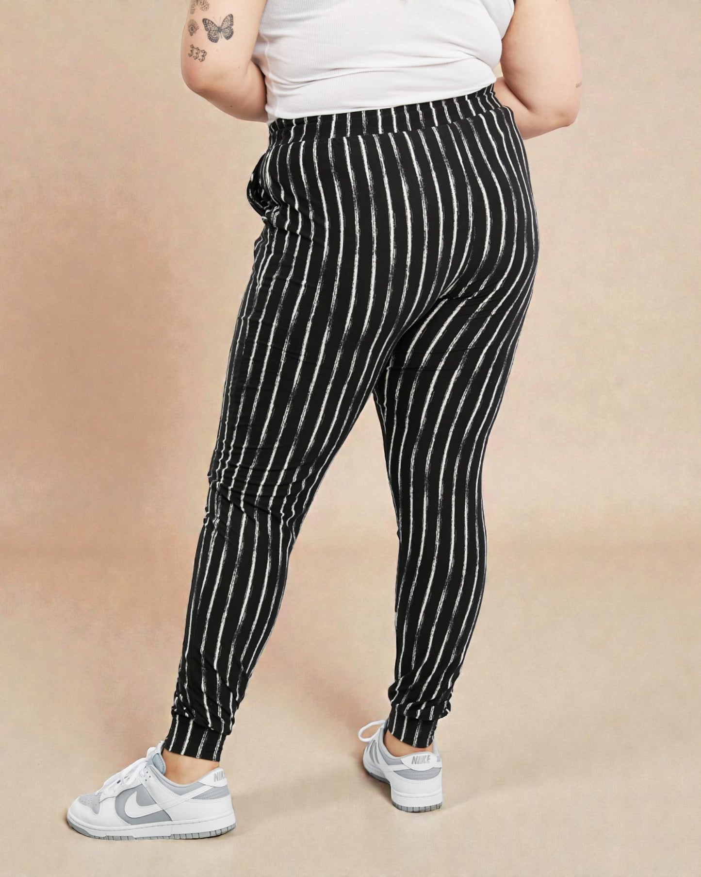 Person wearing black and white striped pants on a beige background