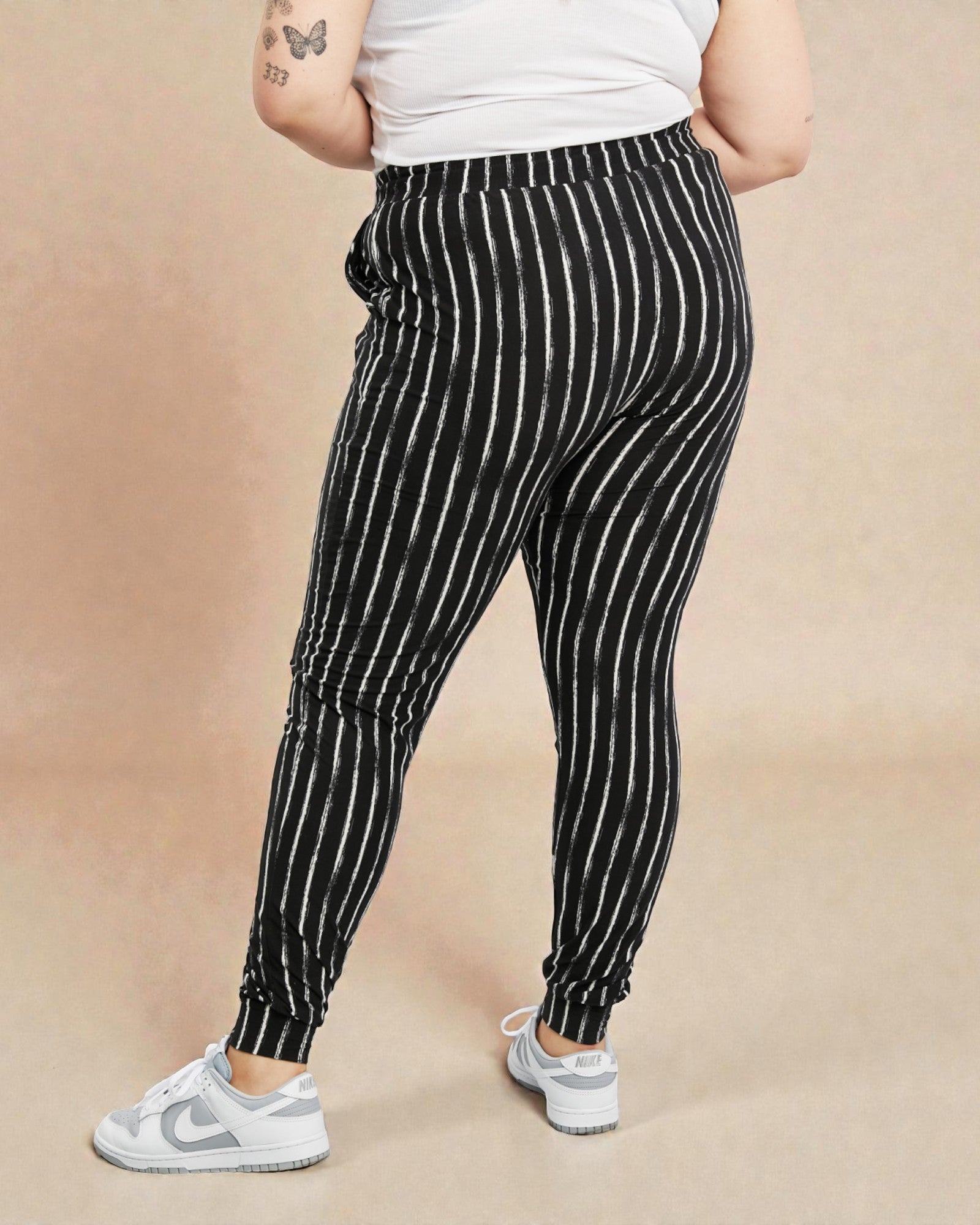 Person wearing black and white striped pants on a beige background