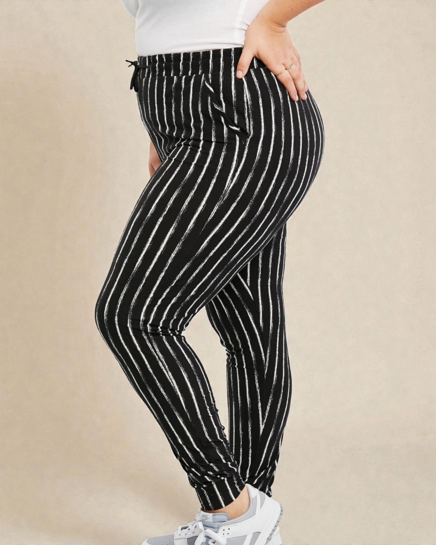 Black and white striped pants worn by a person on a beige background