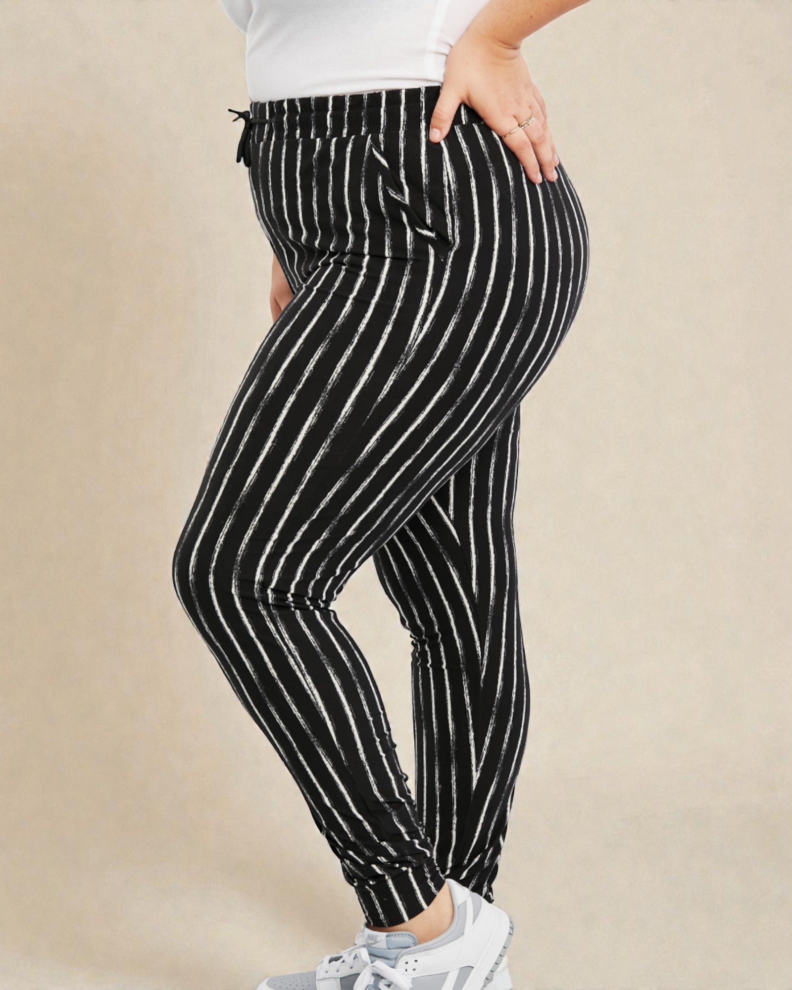 Black and white striped pants worn by a person on a beige background