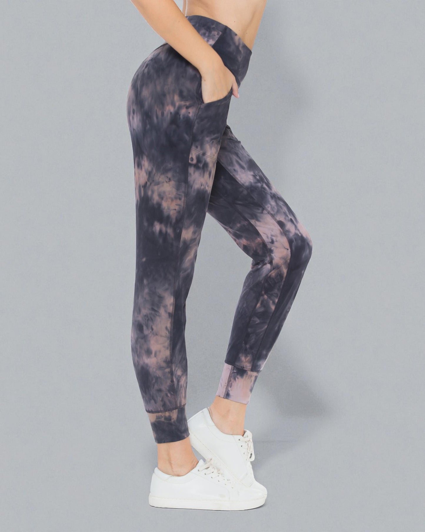 Person wearing tie-dye leggings on a gray background