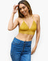 A woman modeling a mustard yellow textured knit triangle bralette top paired with high-waisted blue jeans against a plain white background.