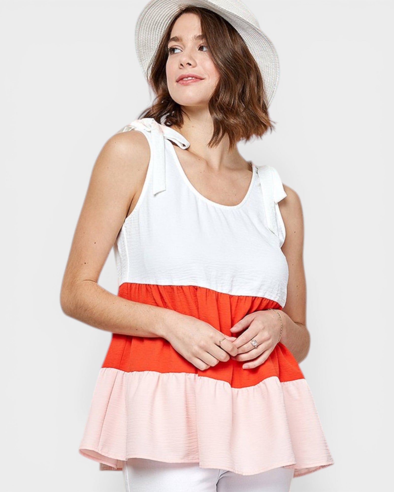Woman wearing a white, red, and pink dress with a white hat on a light gray background