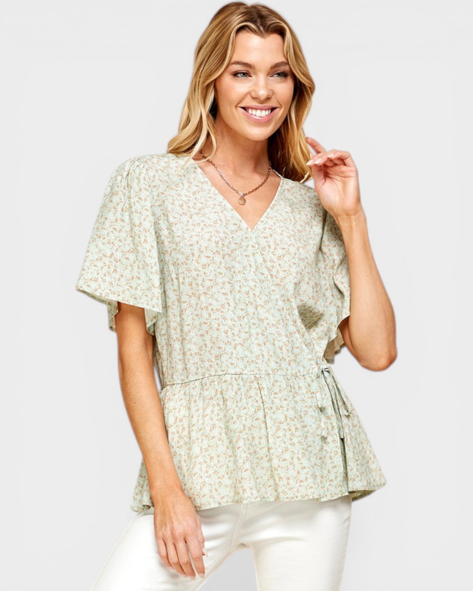 Woman wearing a light green floral blouse against a white background