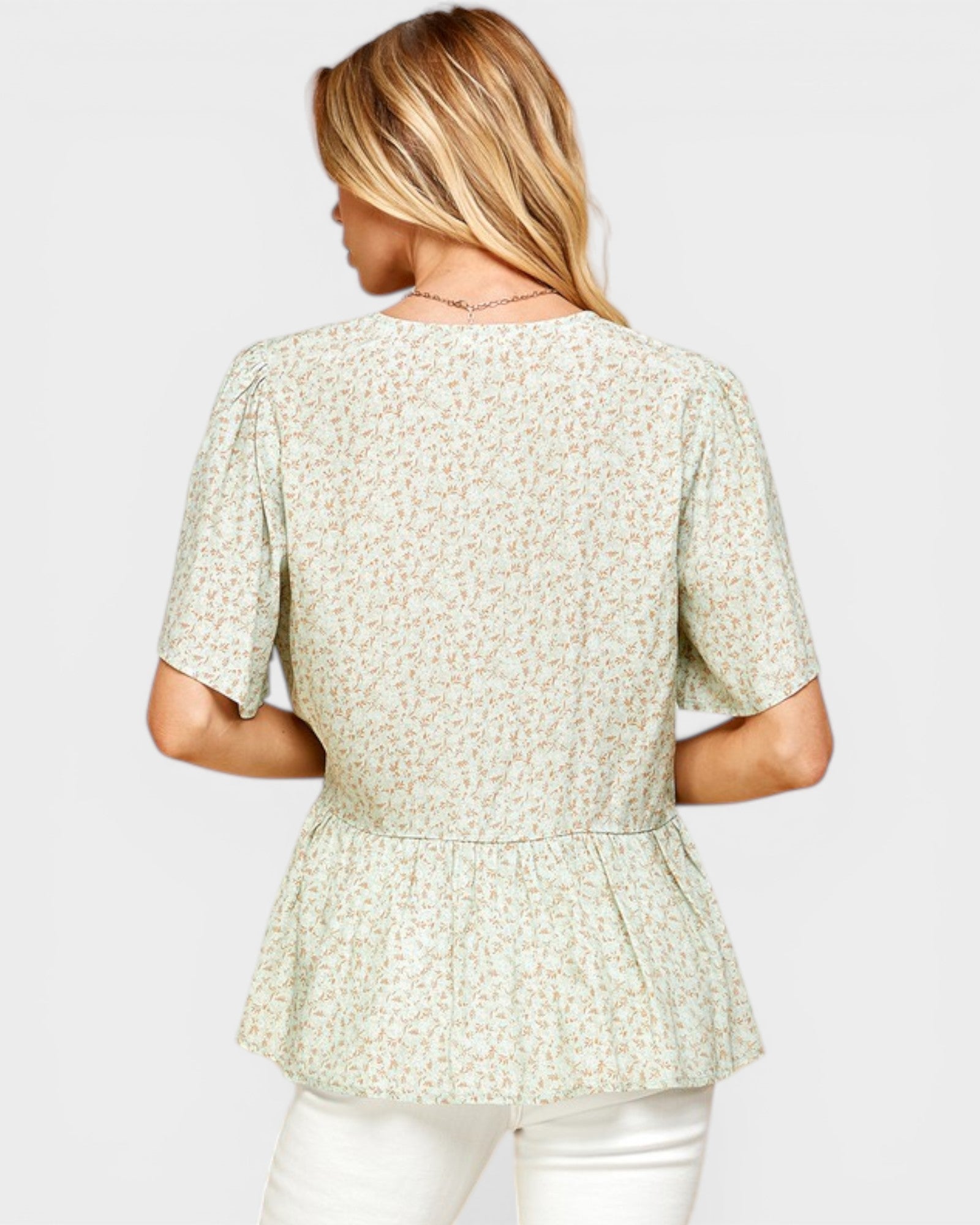 Woman wearing a light green floral blouse on a white background
