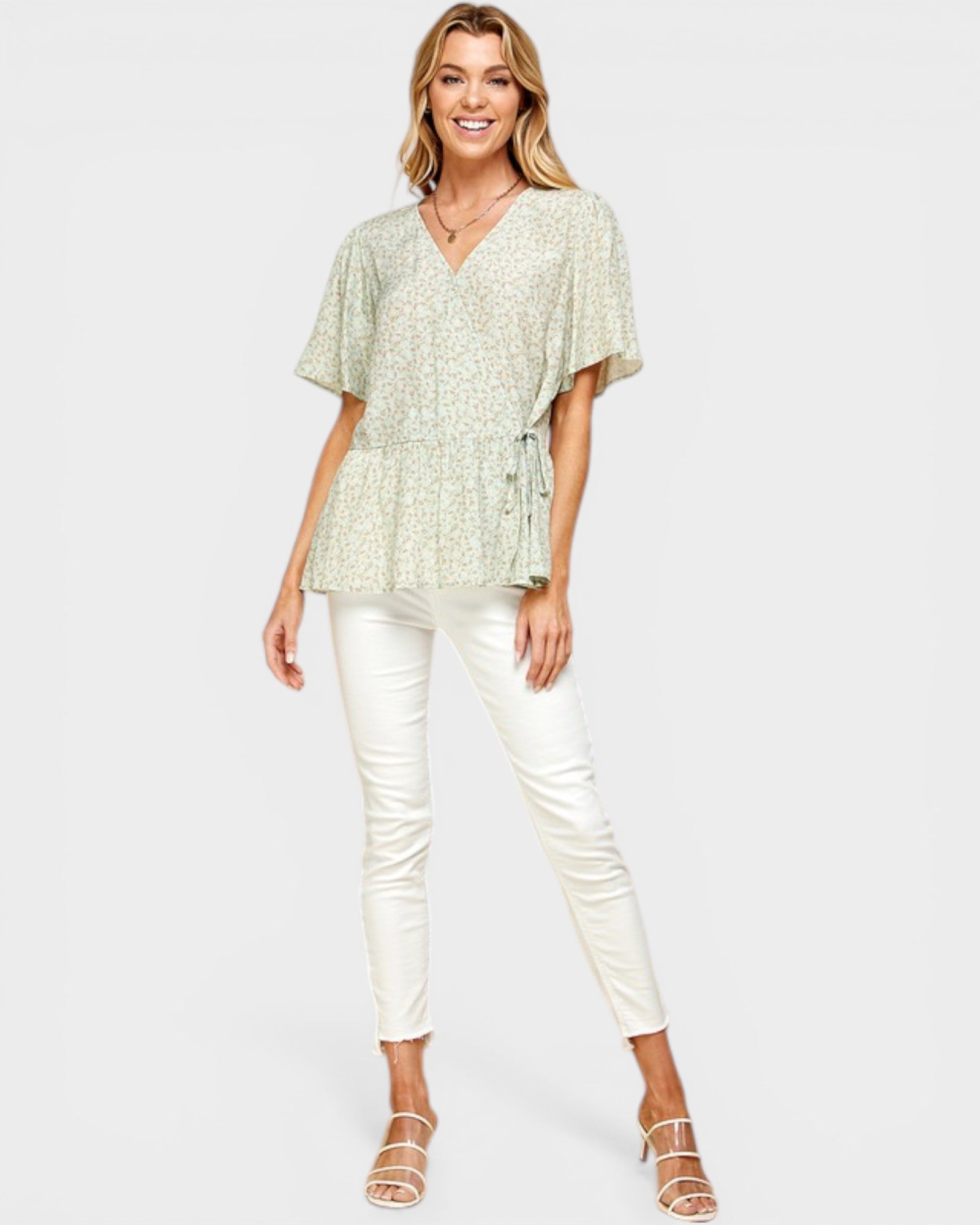 Woman wearing a light green top and white pants on a white background