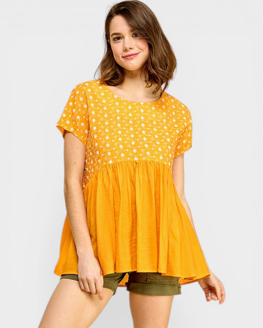 Woman wearing a yellow polka dot blouse and green shorts on a white background
