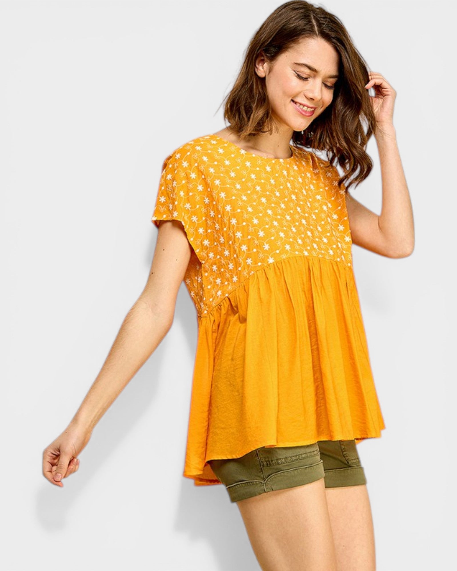 Woman wearing a yellow patterned top and green shorts on a white background