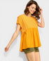 Woman wearing a yellow patterned top and green shorts on a white background