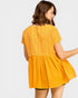 Woman wearing a yellow dress with white polka dots on a plain background
