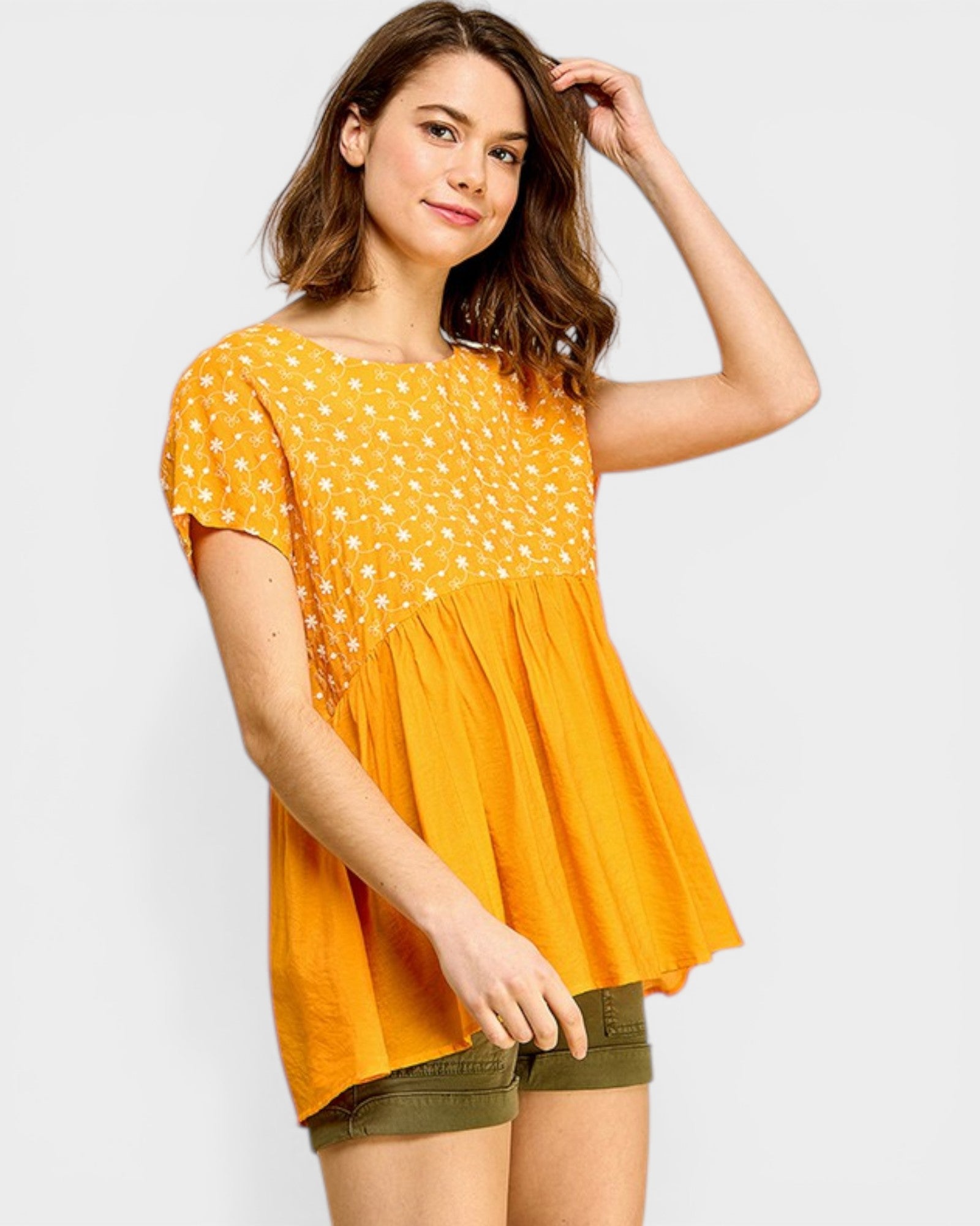 Woman wearing a yellow polka dot top with a plain background