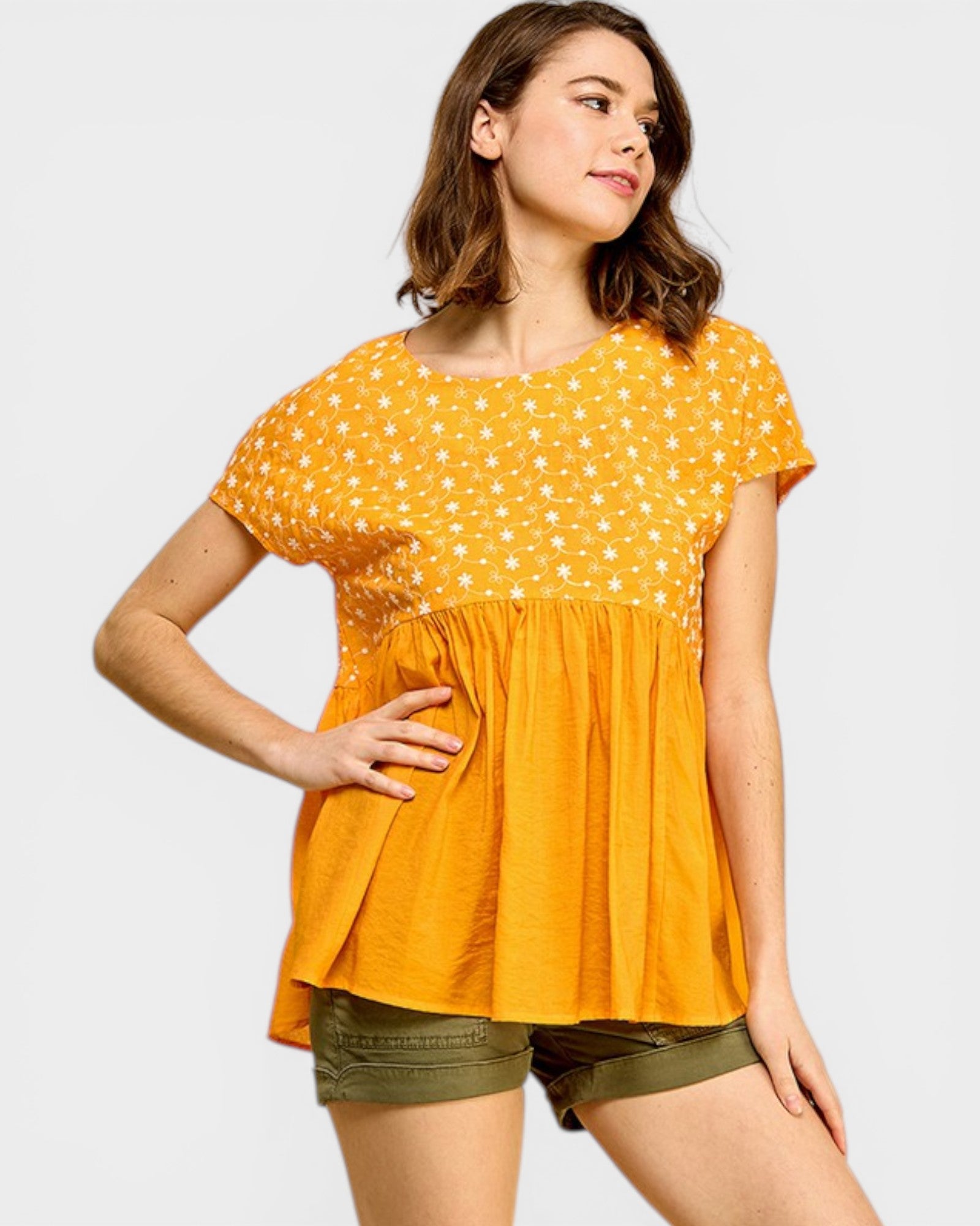 Woman wearing a yellow polka dot blouse and green shorts on a white background