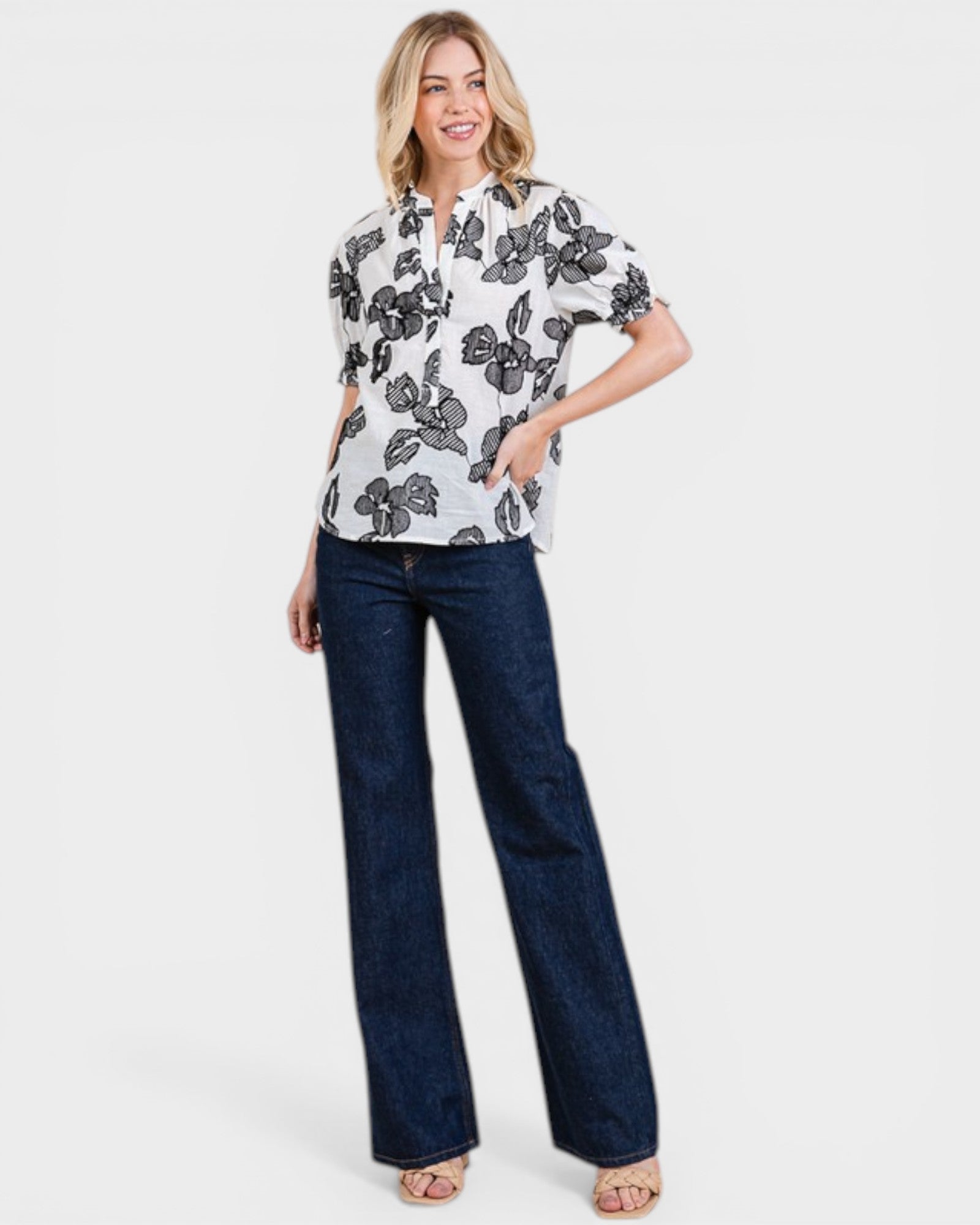Woman wearing a floral blouse and blue jeans on a white background