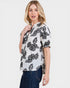 Woman wearing a white blouse with black floral patterns on a white background