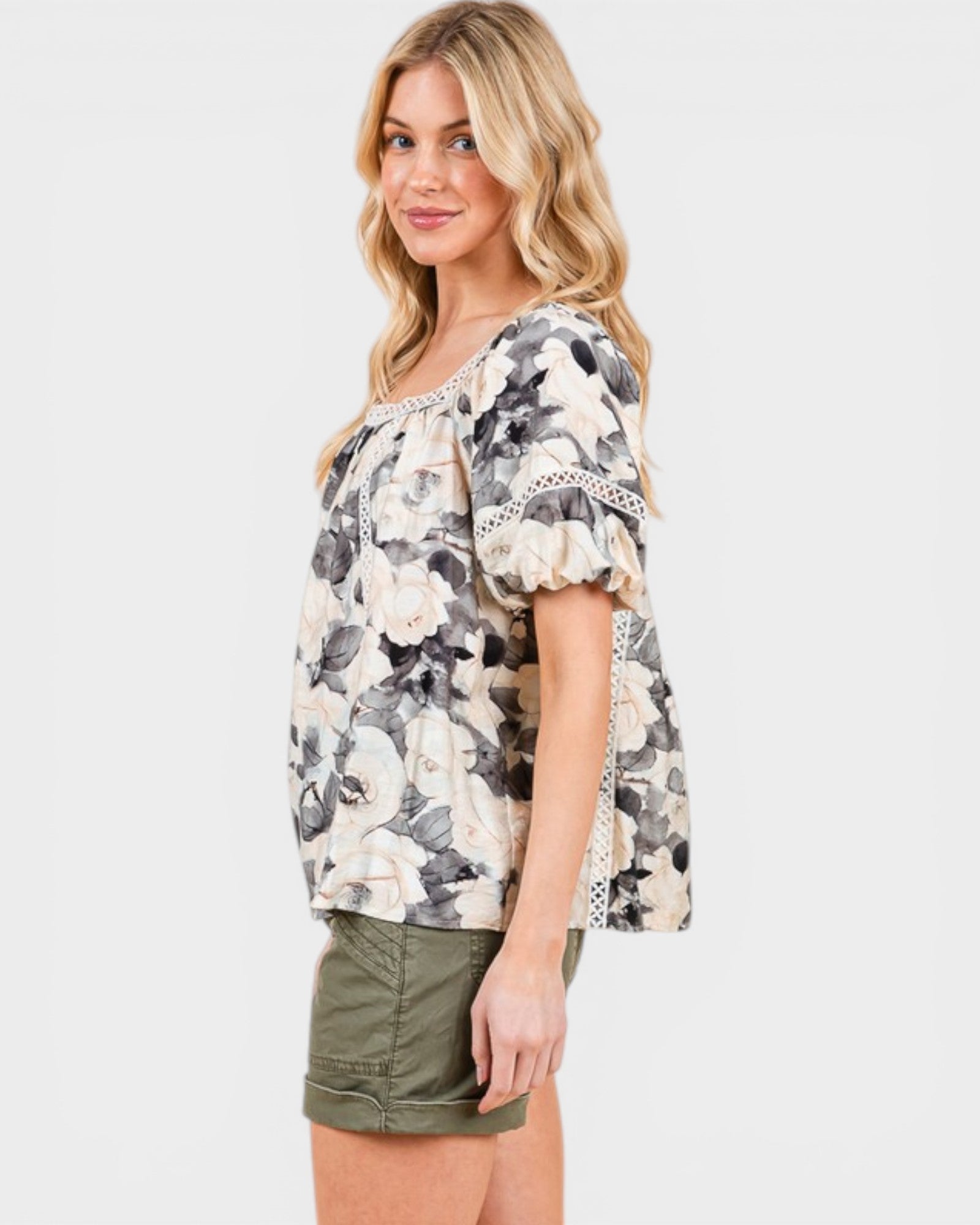 Woman wearing a floral blouse with lace details on a white background