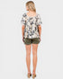 Woman wearing a floral blouse and green shorts on a white background