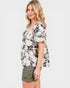 Woman wearing a floral blouse with lace details on a white background