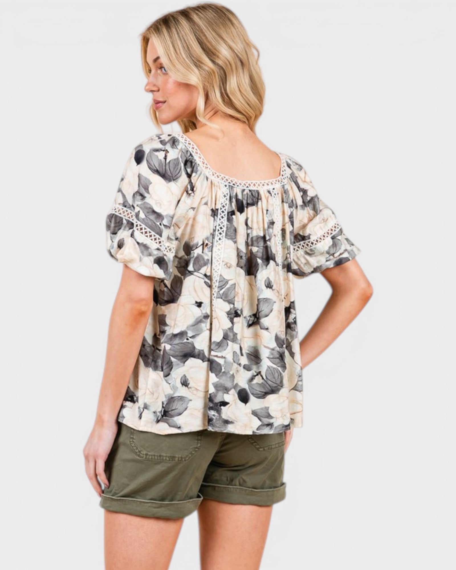Woman wearing a floral blouse and green shorts on a white background