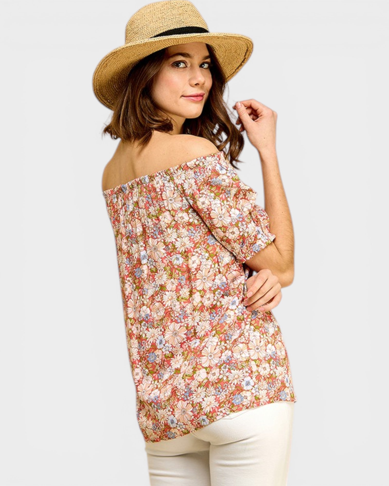 Woman wearing a floral off-shoulder top and wide-brimmed hat on a white background