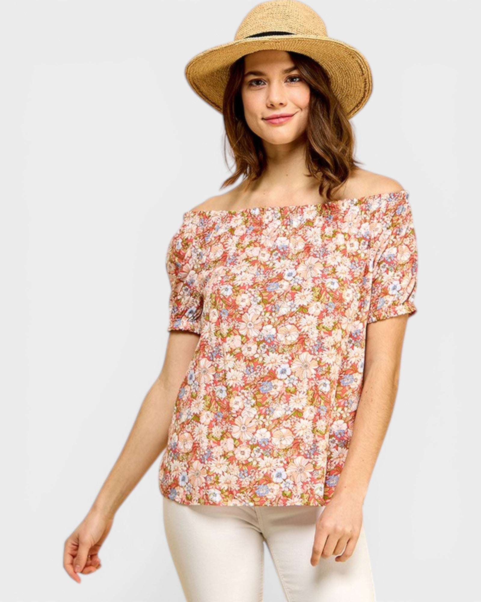 Woman wearing a floral off-shoulder top and straw hat on a white background