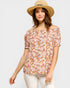 Woman wearing a floral off-shoulder top and straw hat on a white background
