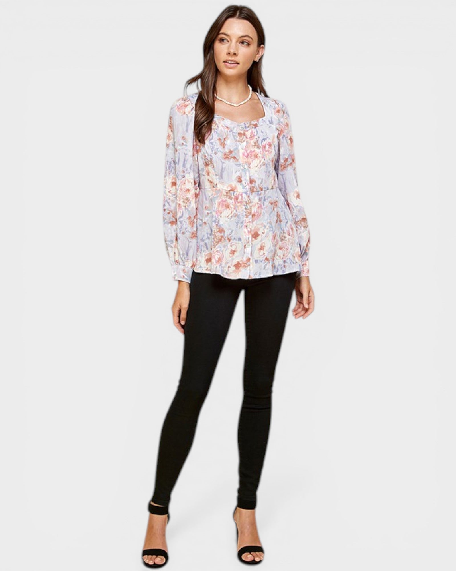 Woman wearing a floral blouse and black leggings on a white background