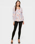 Woman wearing a floral blouse and black leggings on a white background