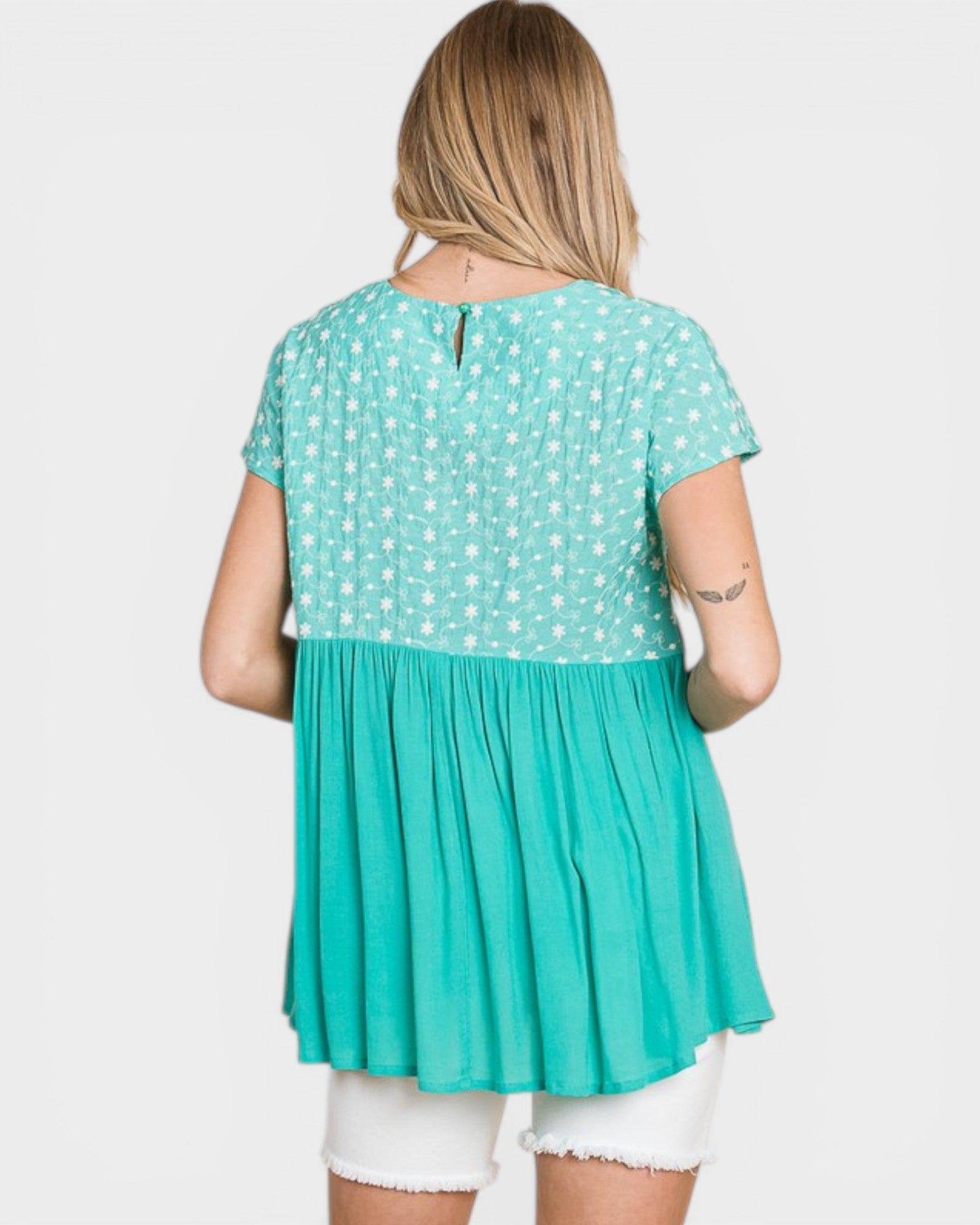 Woman wearing a teal dress with white polka dots on a light gray background