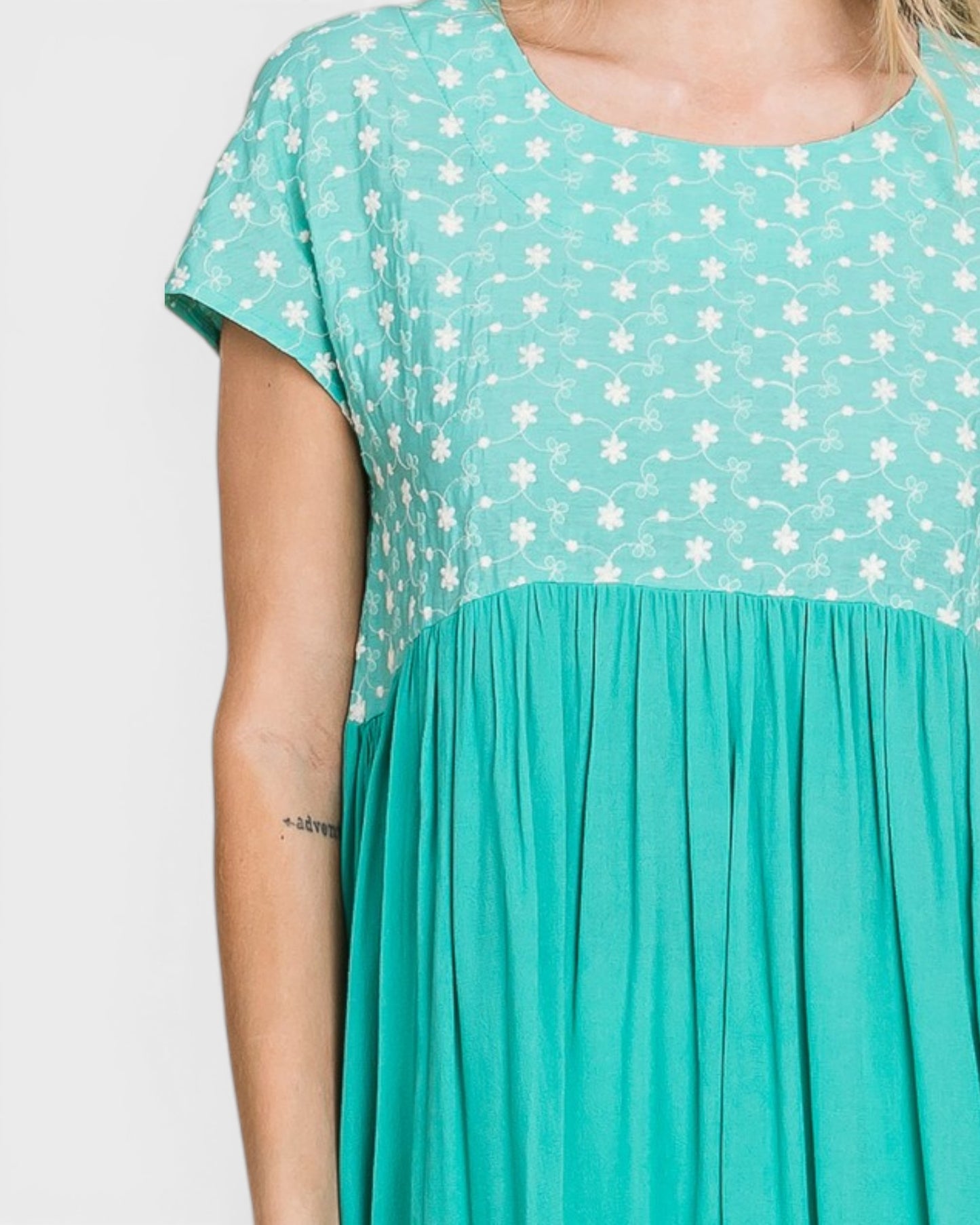 Teal dress with white floral pattern on a plain background